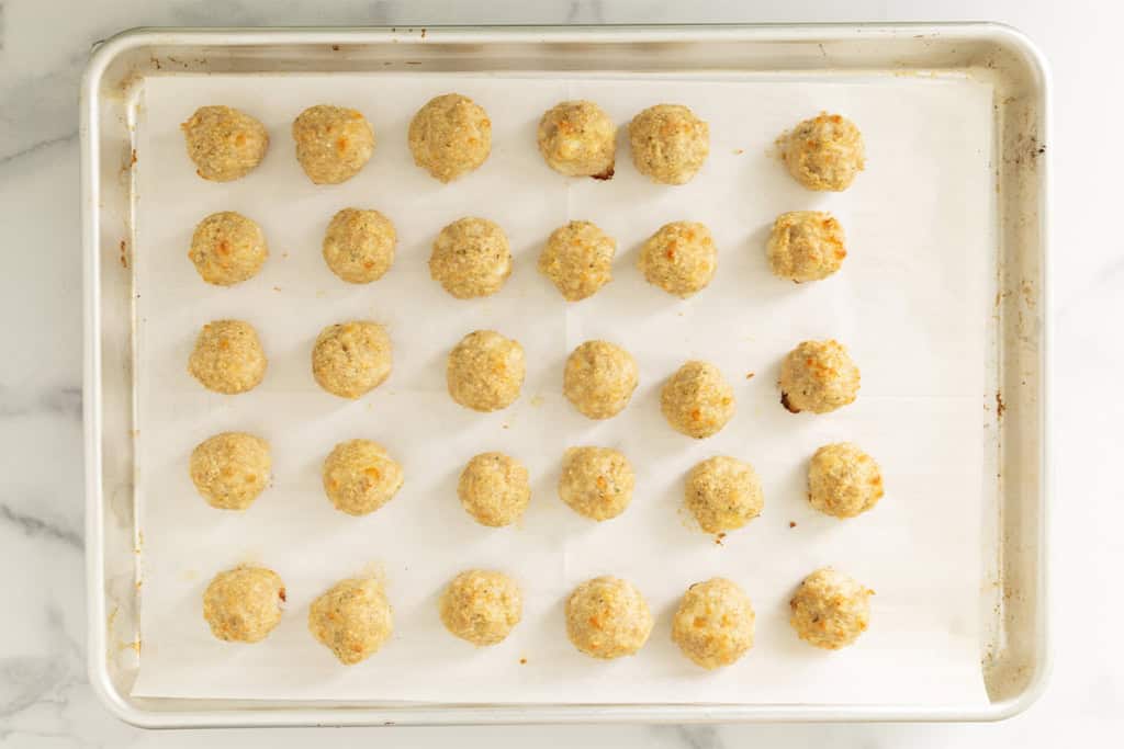 Chicken parmesan meatballs on baking sheet after baking.