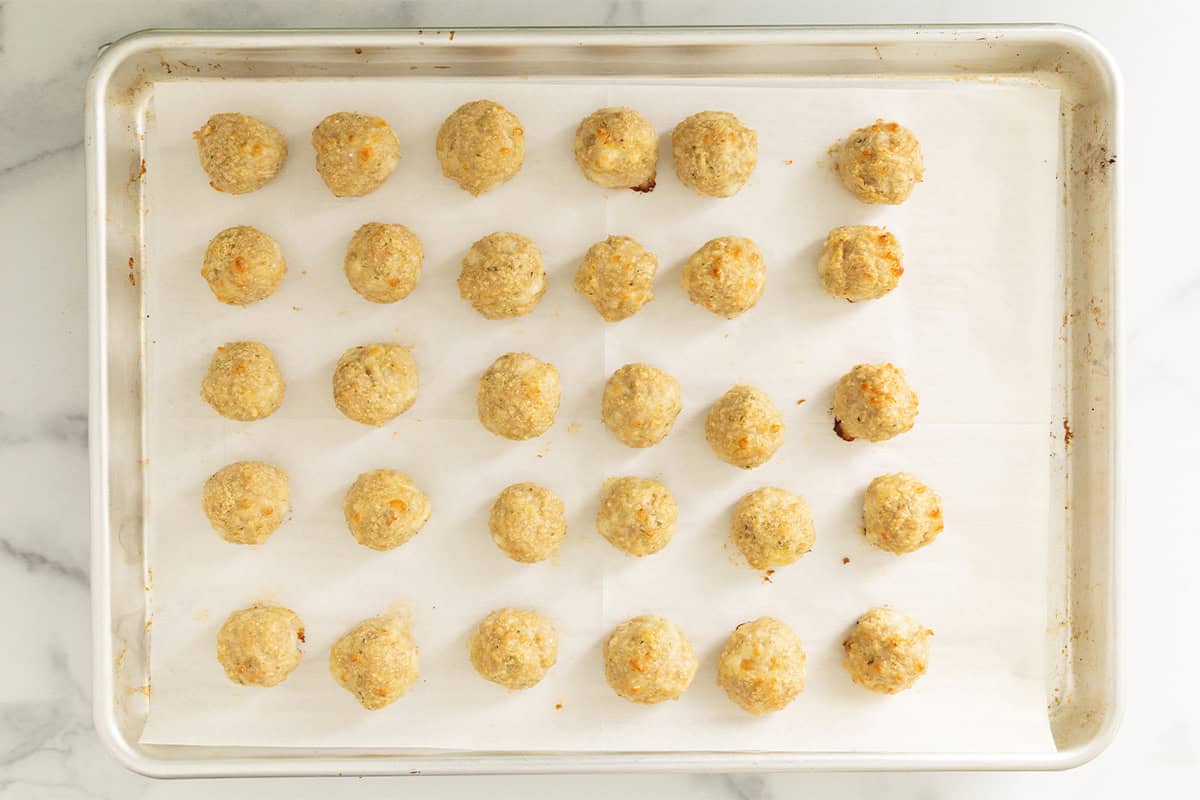 Chicken parmesan meatballs on baking sheet after baking.