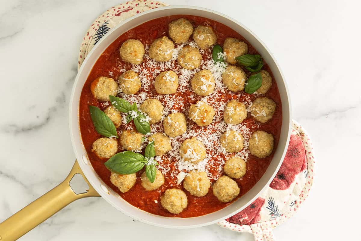 Chicken parmesan meatballs in pan with tomato sauce.