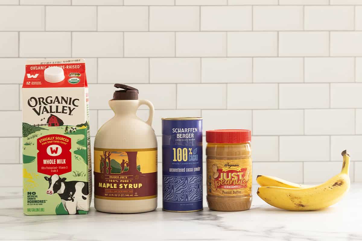 Ingredients for chocolate peanut butter banana smoothie on countertop.