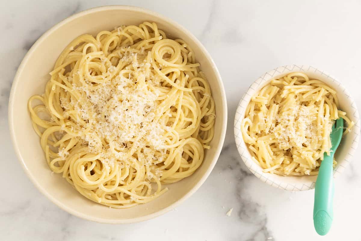 Parmesan noodles in two bowls with blue spoon.