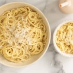 Parmesan noodles in two bowls with blue spoon and cup.