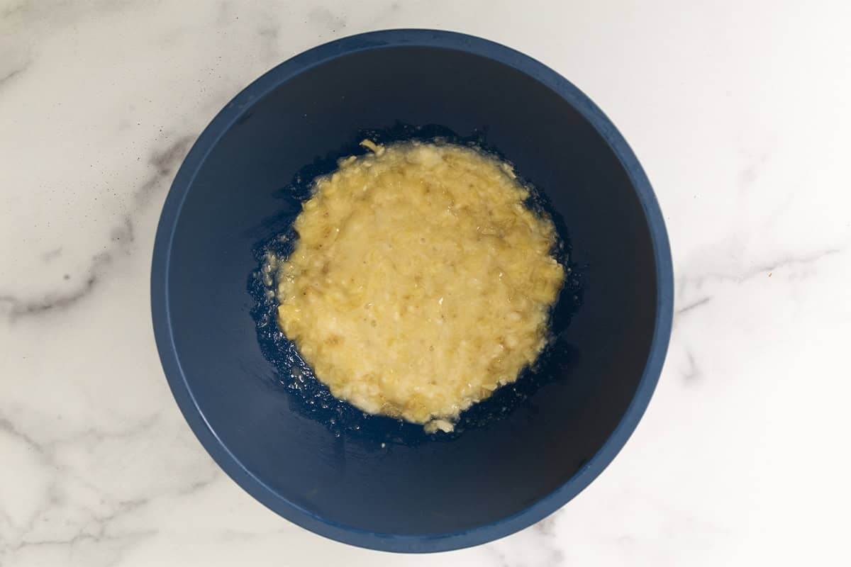 Mashed banana in blue bowl for peanut butter oatmeal bars.