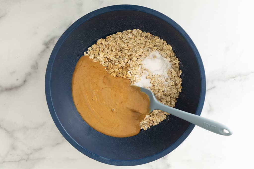 Ingredients for pb oatmeal bars in blue bowl before mixing.