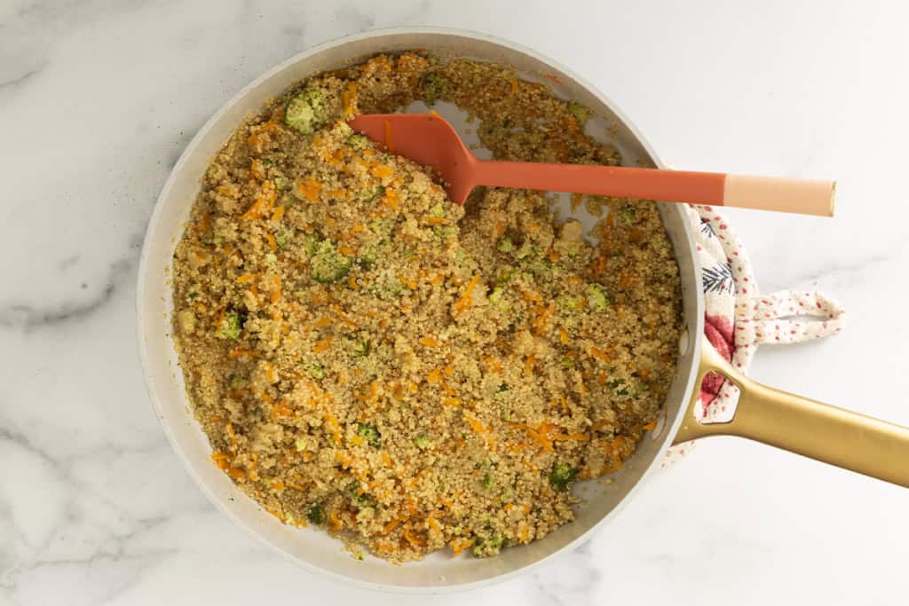 Veggie quinoa in pot with red spoon.