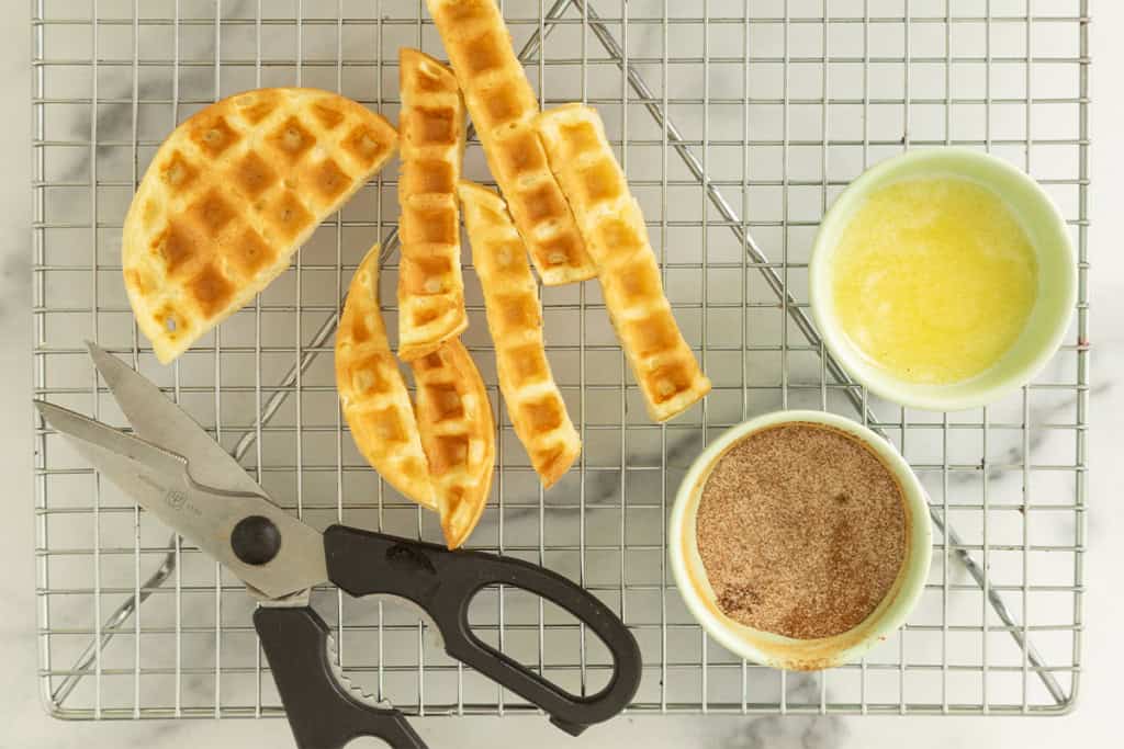 Cutting waffles into sticks with cinnamon sugar and butter on side.