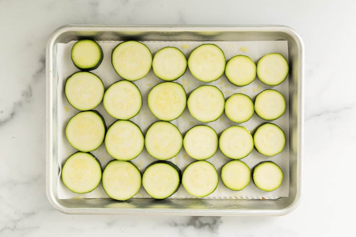 Slices of zucchini on baking sheet for zucchini pizza.