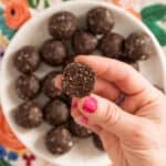 chocolate bliss balls in hand with pink nails.