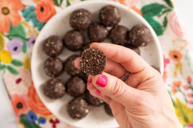 chocolate bliss balls in hand with pink nails.