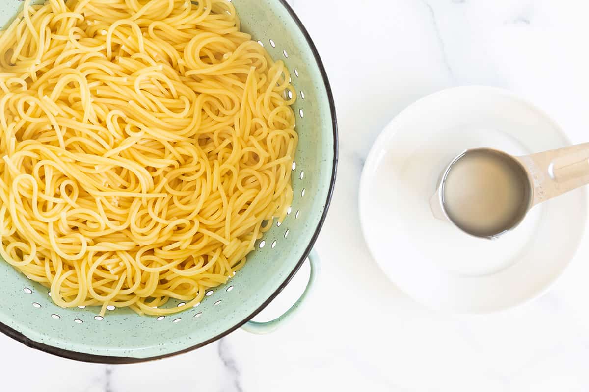 Noodles in strainer with pasta water on side for parmesan noodles.
