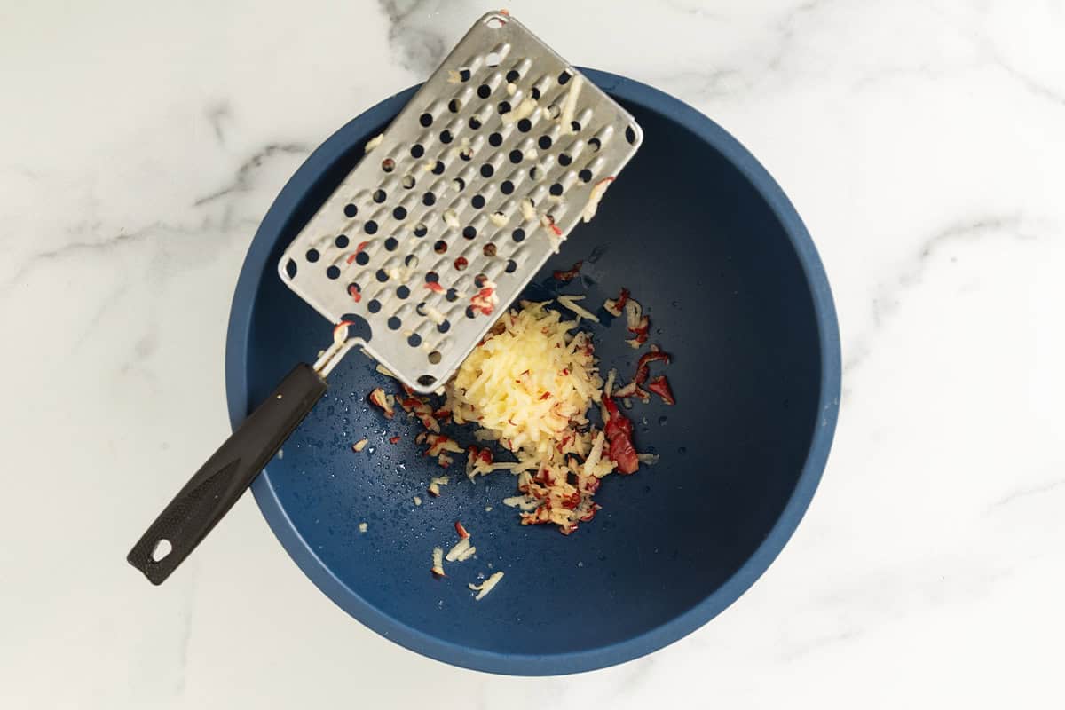 Grating apple in to blue bowl.