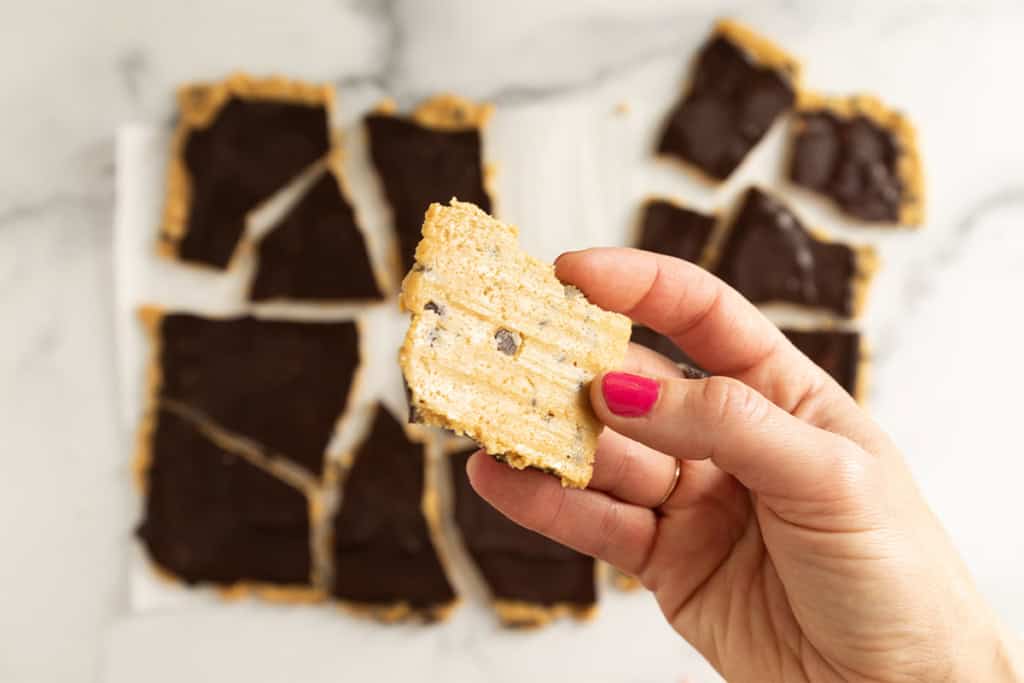 Hand holding piece of cookie dough bark.