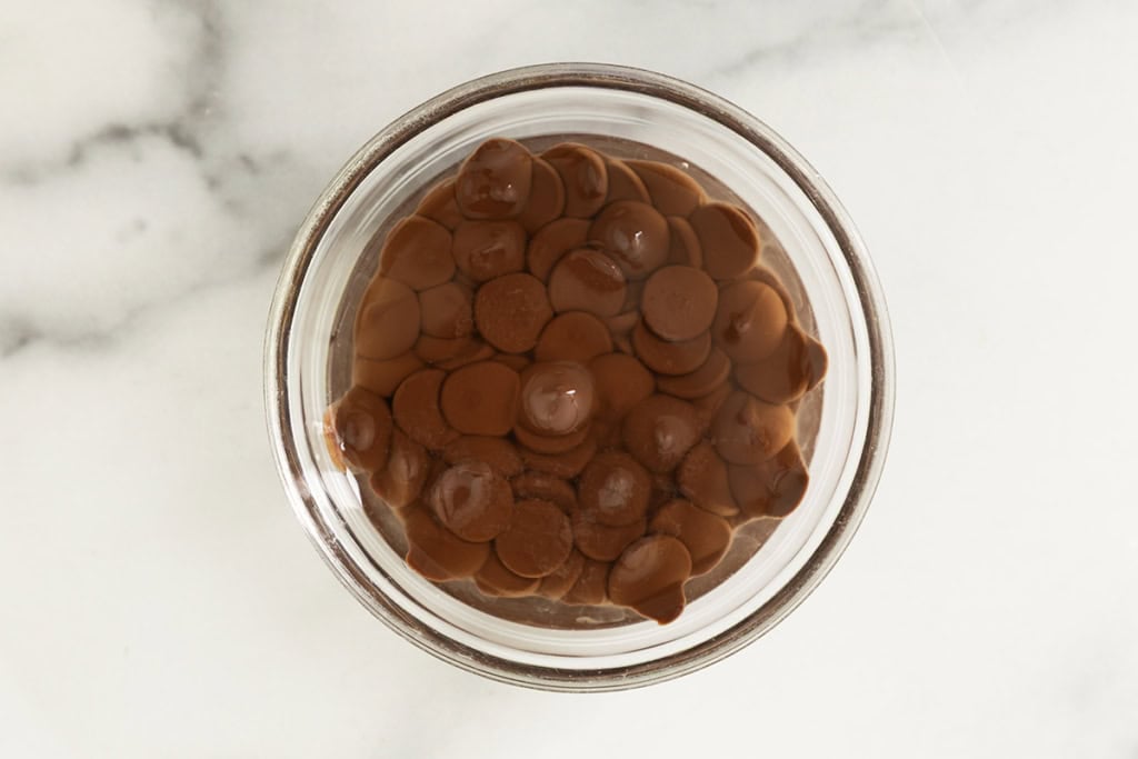 Chocolate chips with melted oil in glass bowl for magic chocolate shell.