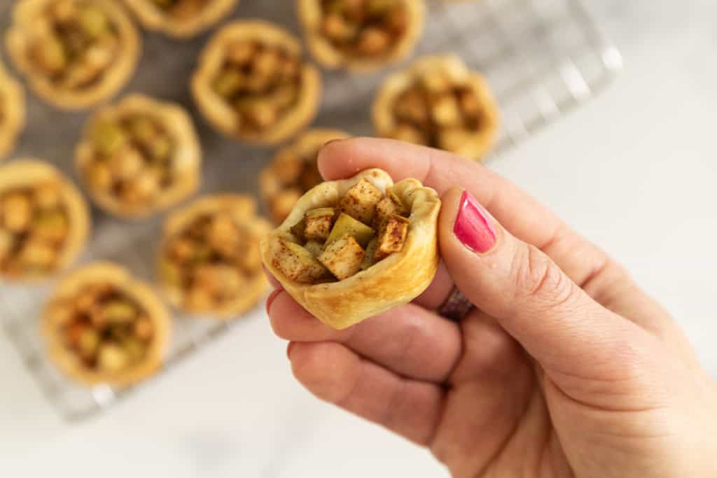 Hand holding mini apple pie.