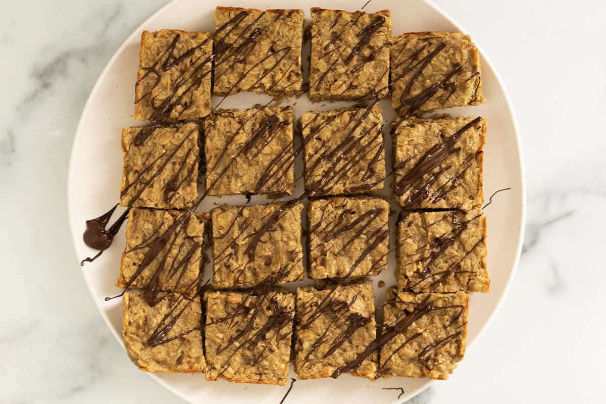 sliced peanut butter oatmeal bars with chocolate drizzle on plate.