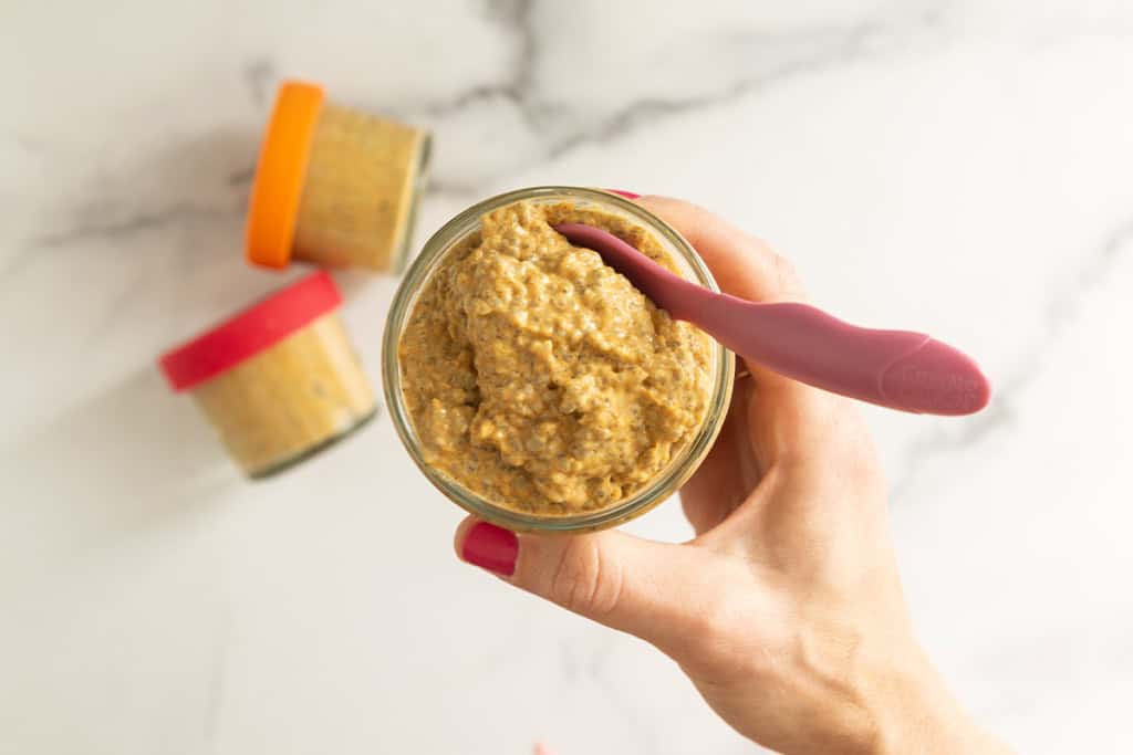 Hand holding jar of pumpkin chia seed pudding.