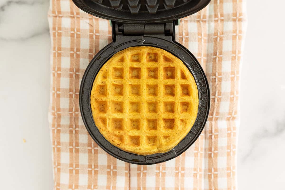 Pumpkin waffles in waffle iron after cooking.