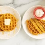 Pumpkin waffles on two plates with butter.