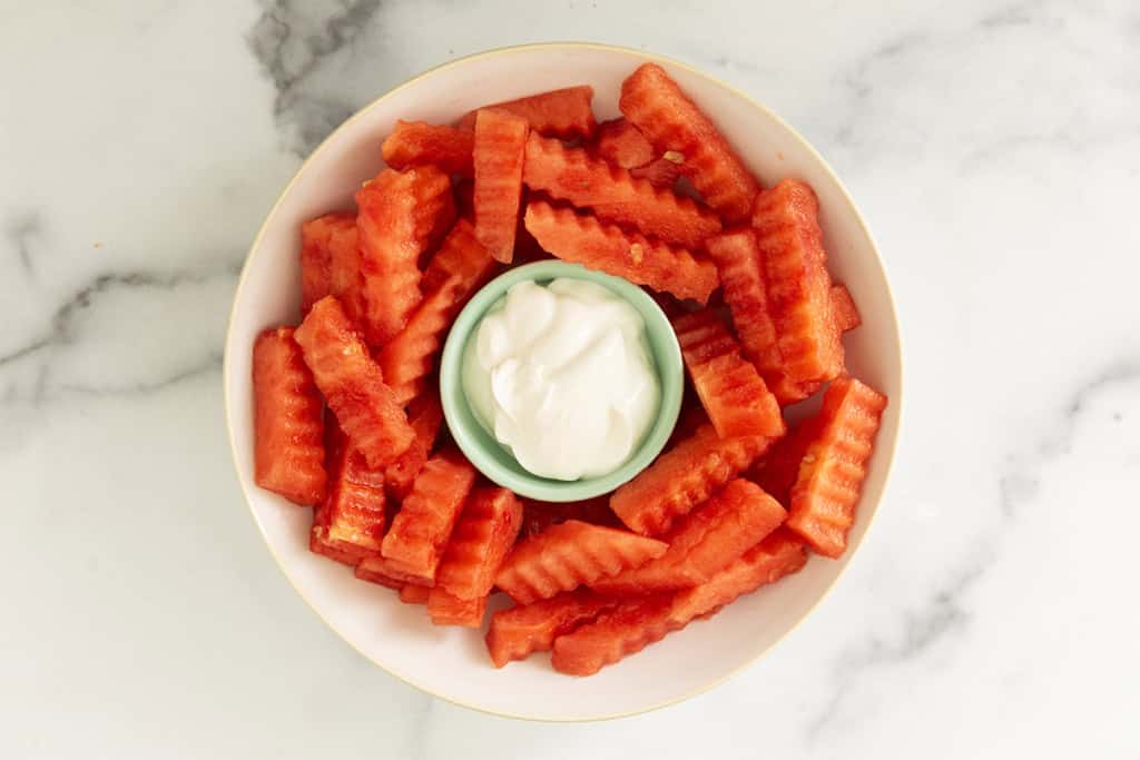 Watermelon fries with yogurt on white plate.