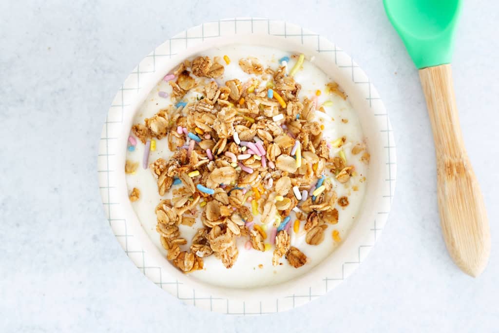 Lower sugar granola on yogurt in white bowl.