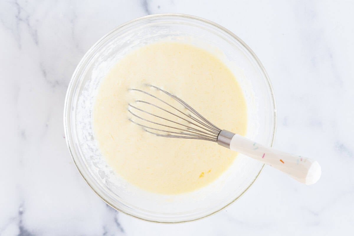 wet ingredients for mini waffles in mixing bowl with whisk.