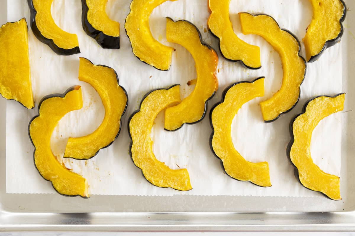 Acorn squash slices on a baking sheet.