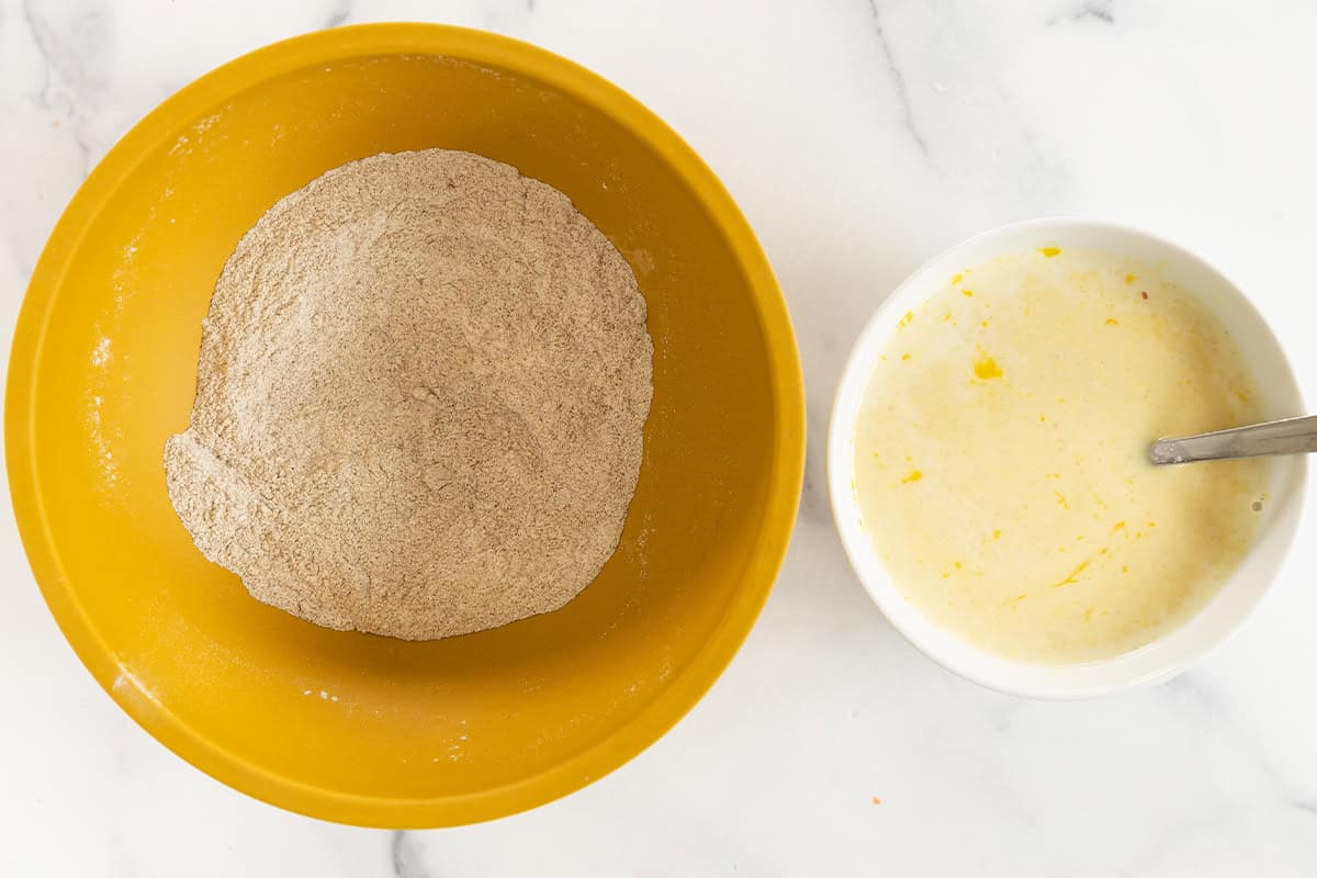 Dry and wet ingredients for applesauce pancakes in separate bowls.