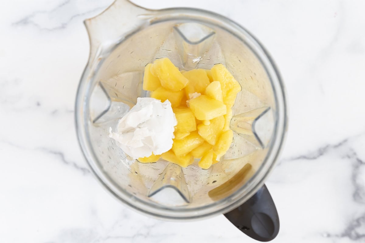Pineapple chunks and coconut cream in a blender.