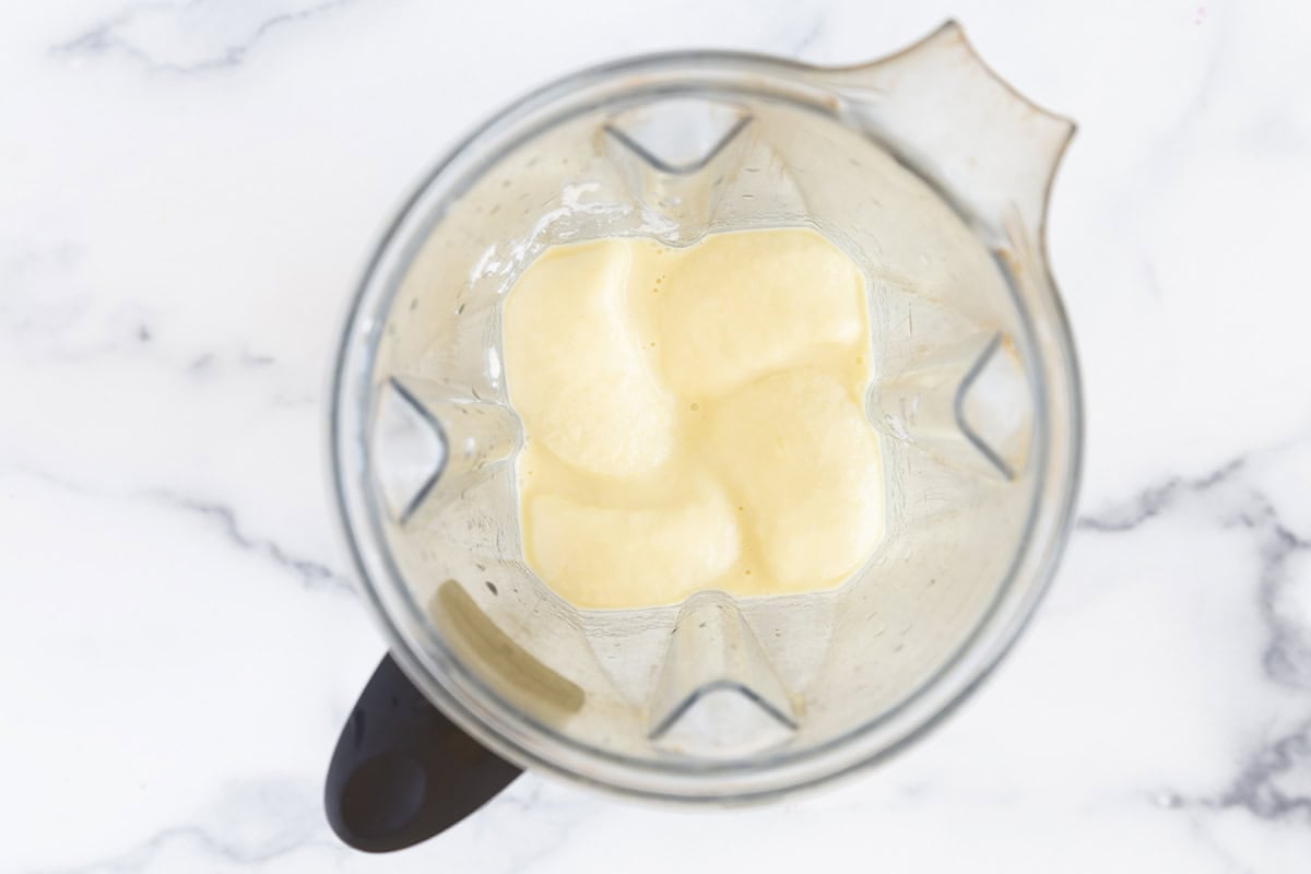 Blended pineapple popsicle mixture in a blender.
