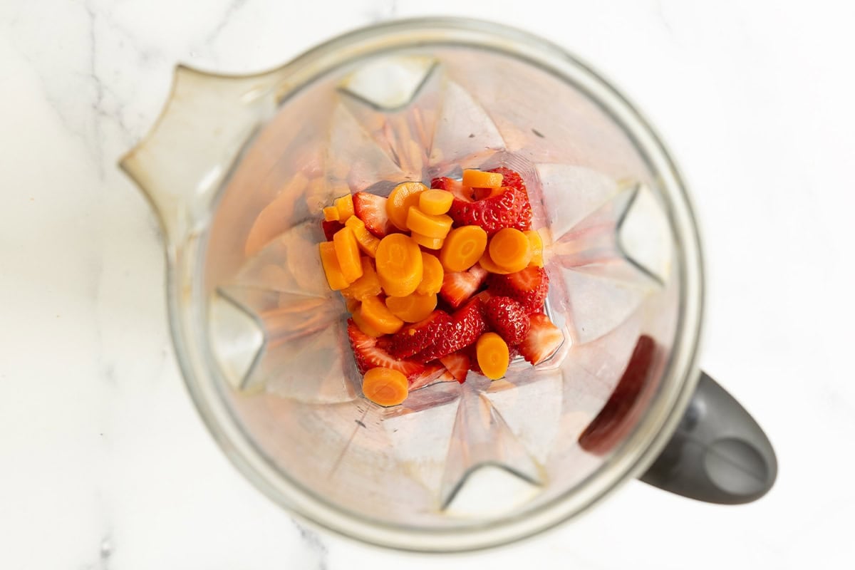 Strawberries and carrots in a blender.