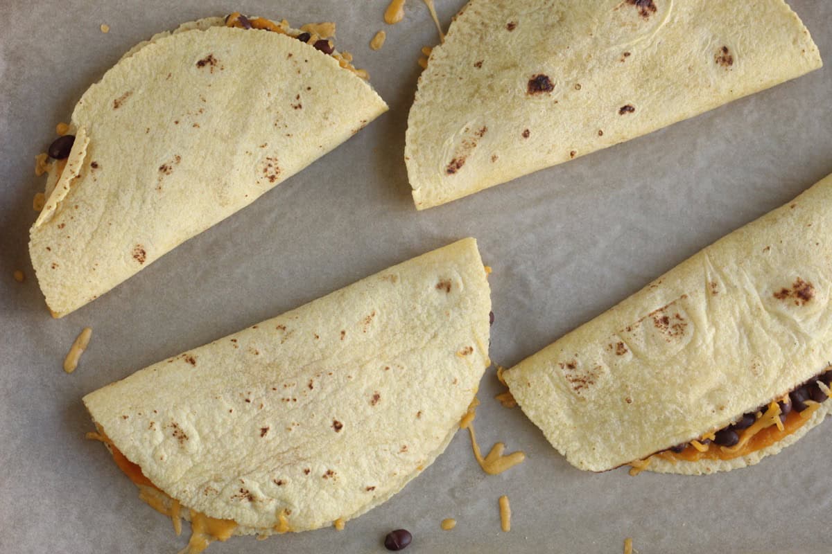 Folded black bean quesadillas on a baking sheet.