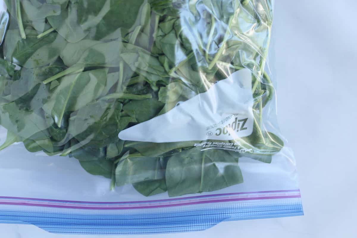 Sealed freezer bag filled with fresh spinach.