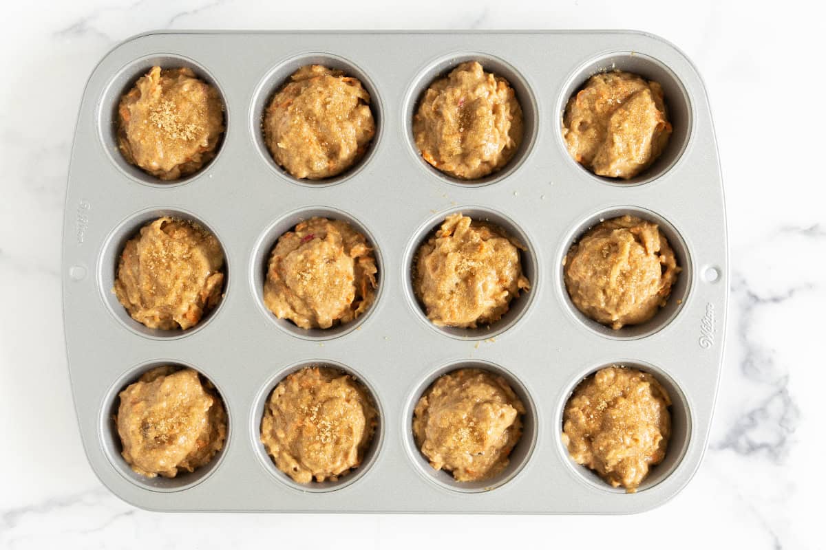 Morning glory muffin batter in a muffin pan.