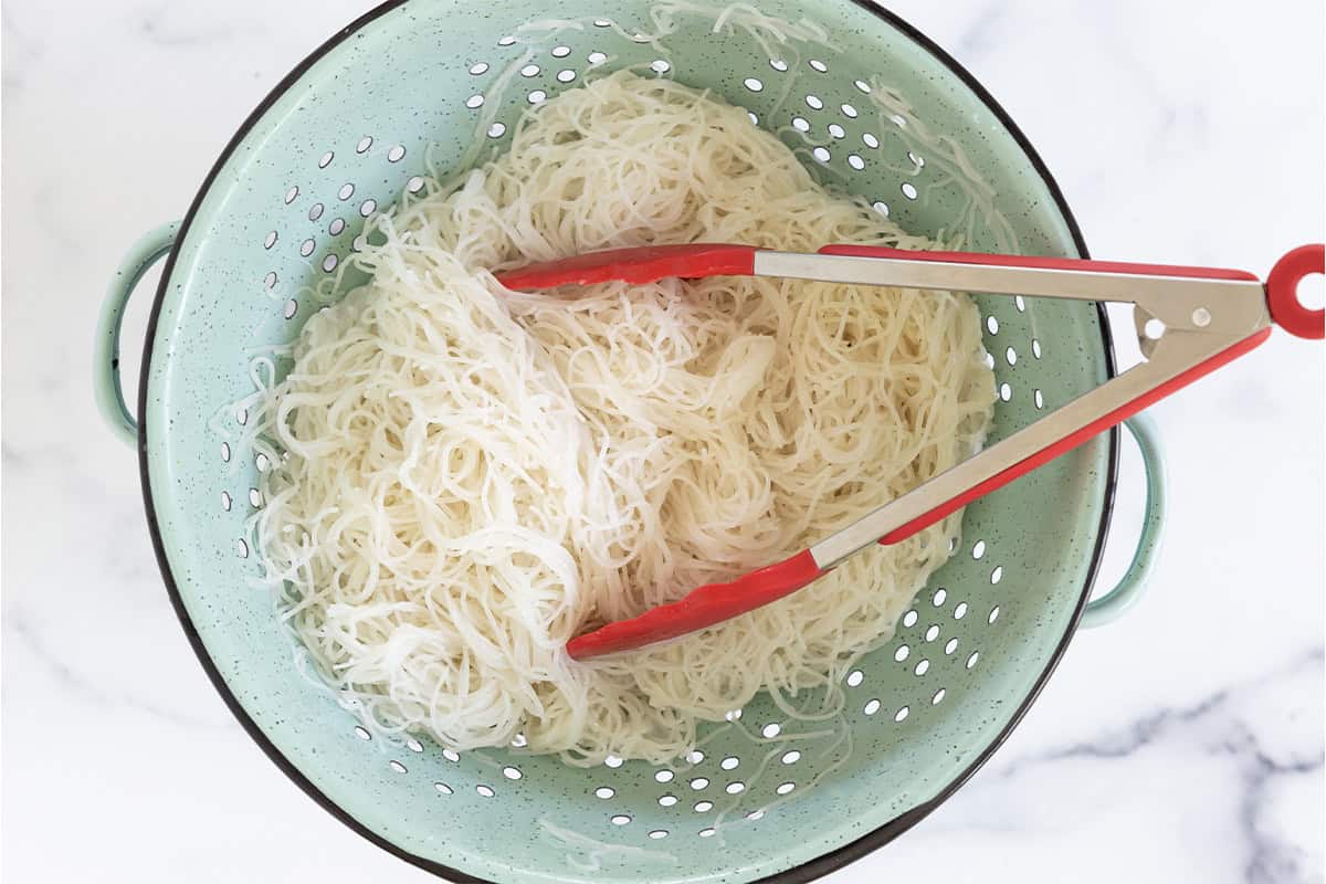 Rice noodles in a colander.