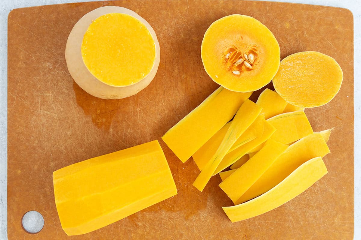 Peeled butternut squash cut into rounds on a cutting board.