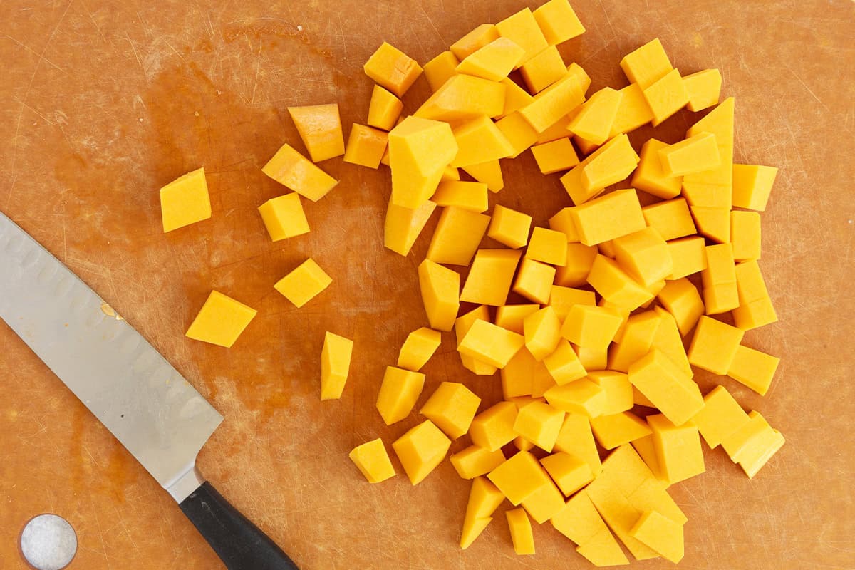 Butternut squash cut into cubes on a cutting board.