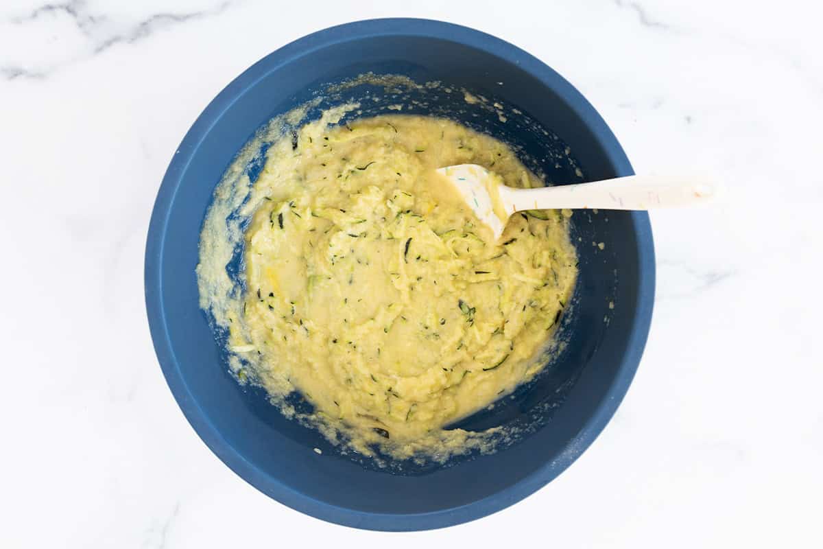 Wet zucchini cake ingredients in a blue bowl.