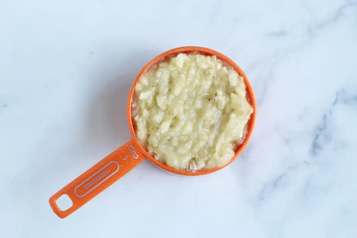 Mashed banana in an orange measuring cup.