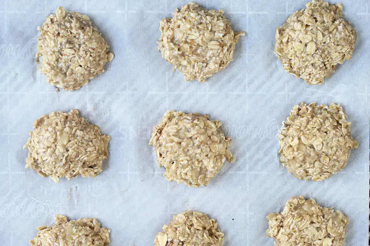 Banana cookie dough scooped onto a parchment-lined baking sheet.