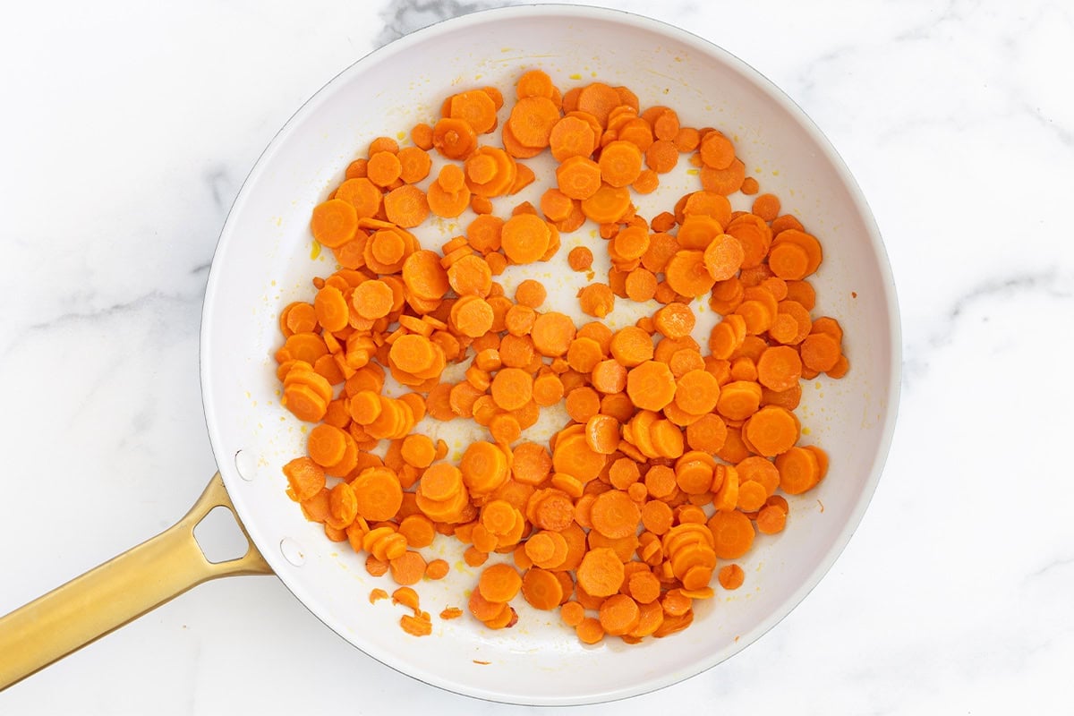 Saut&eacute;ed carrot rounds in a skillet.