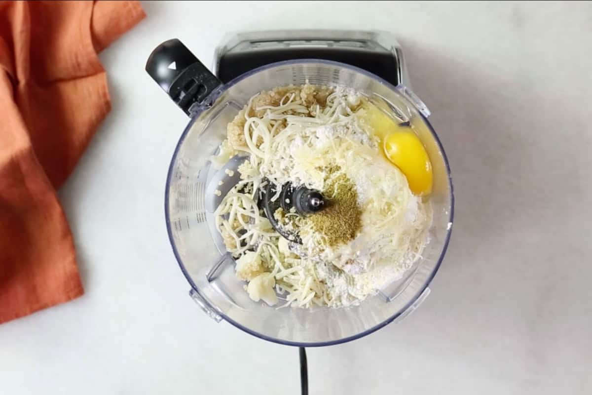 Cauliflower tot ingredients in a food processor.