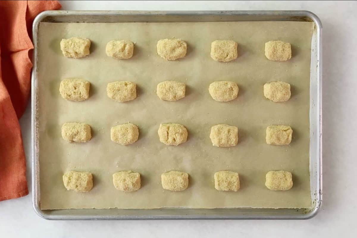 Unbaked cauliflower tots arranged on a baking sheet.