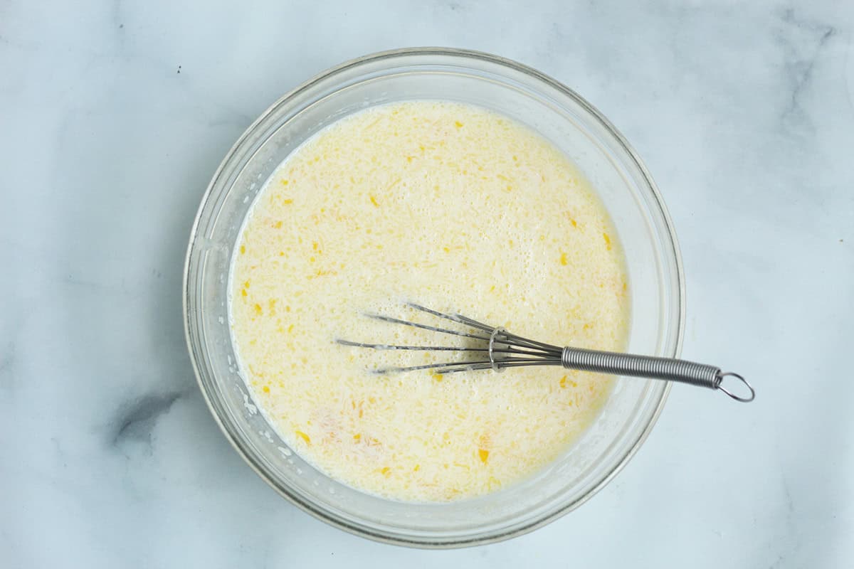 Wet pancake ingredients whisked in a glass bowl.