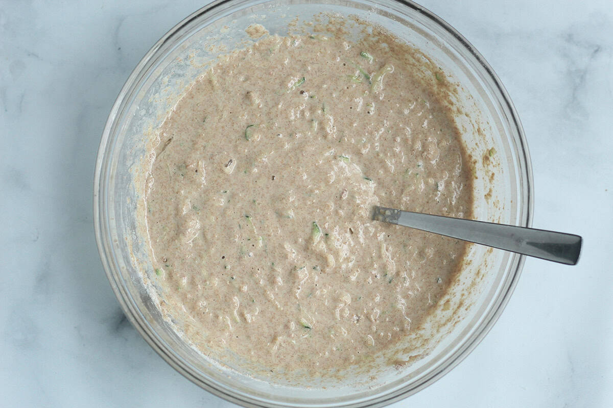 Zucchini pancake batter mixed in a glass bowl.