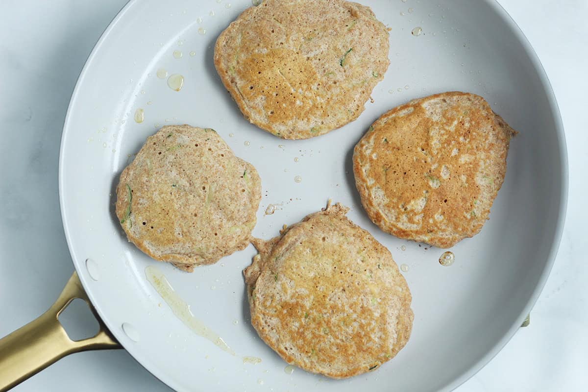 Cooked zucchini pancakes in a skillet.