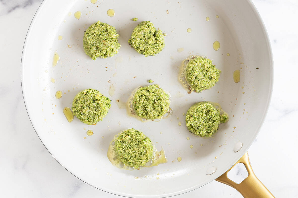Uncooked broccoli fritters in a skillet.