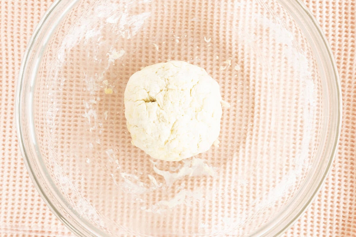 Greek yogurt pizza dough formed into a ball in a glass bowl.
