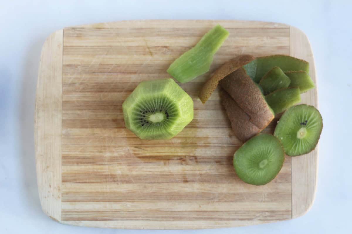 Peeled kiwi with skin on a cutting board.