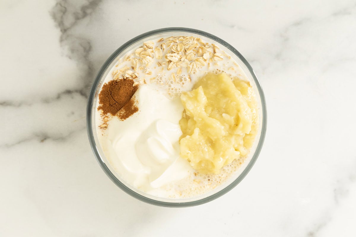 Milk, yogurt, mashed banana, oats, and cinnamon in a bowl for banana overnight oats.