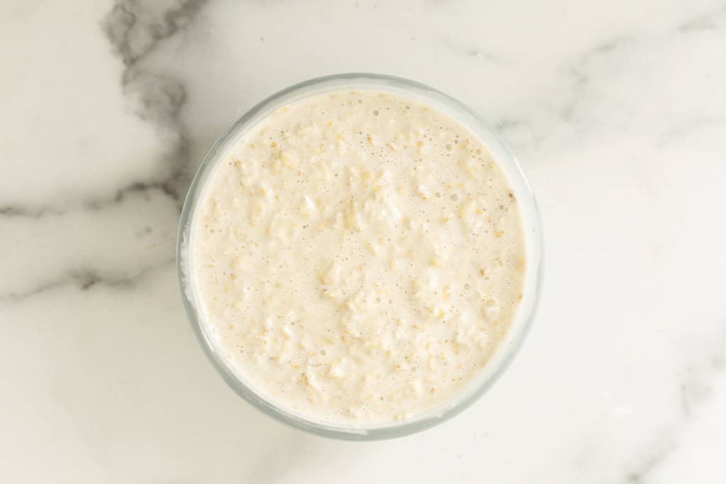 Banana overnight oats mixture stirred together in a glass bowl.